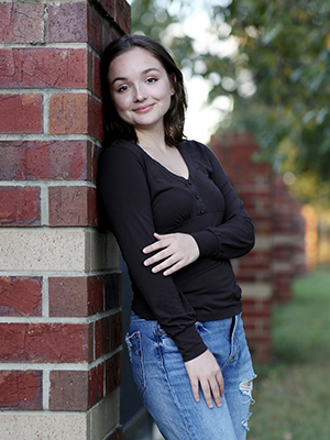 Annika Trout leaning against brick building